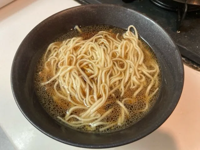 茹で上がった麺を湯切りしてスープを入れた丼に入れる