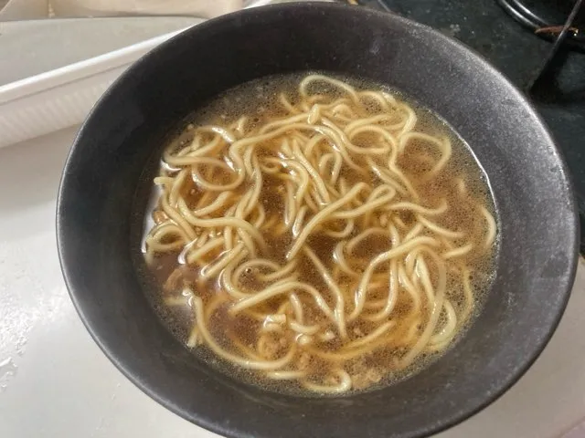 茹で上がった麺を湯切りしてスープを入れた丼に入れる